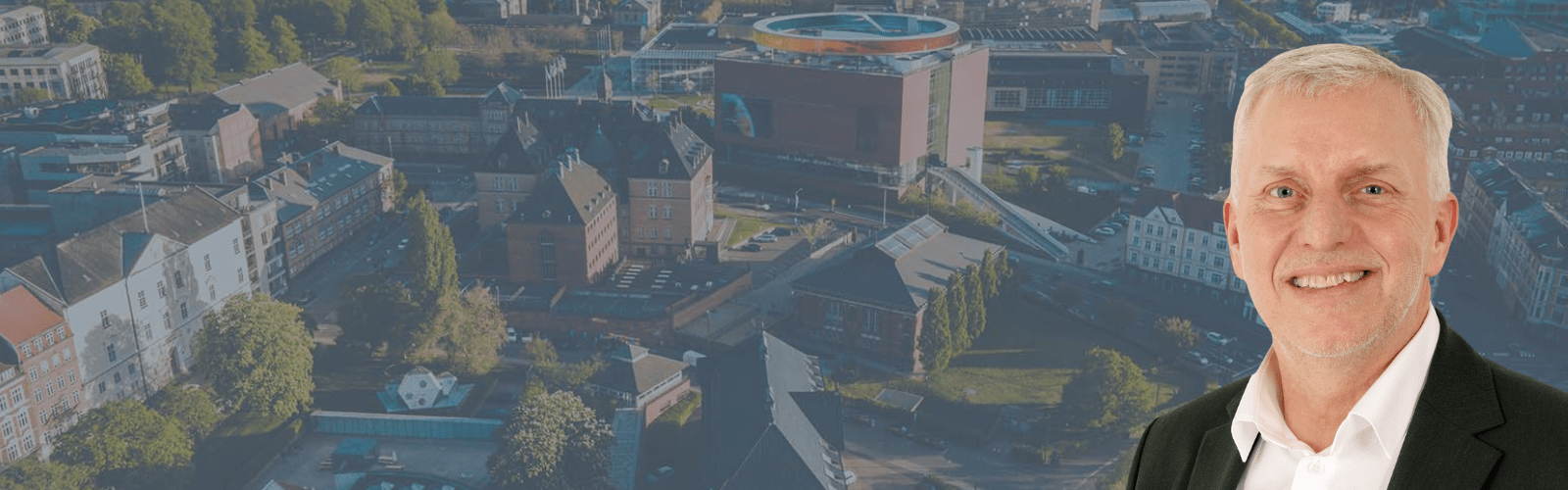 Bo Dall-Hansens portrætfoto foran luftfoto af Aarhus midtby